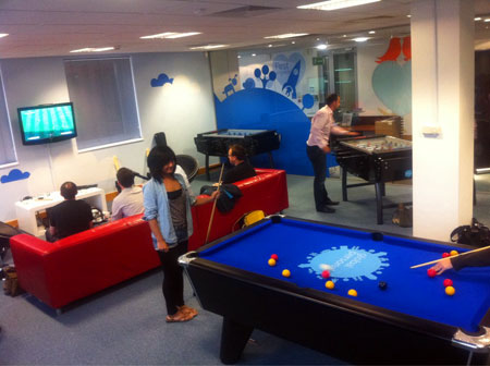 A photograph of the globaldev games room in use with pool table, football tables and Xbox