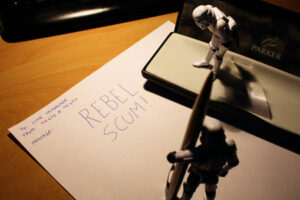 An image of two Star Wars Stormtrooper toy figures penning a letter to Luke Skywalker saying Rebel Scum