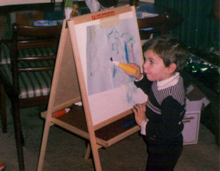 An old photograph of Sam Barnes as a child painting a bad picture on a child's standing upright easel