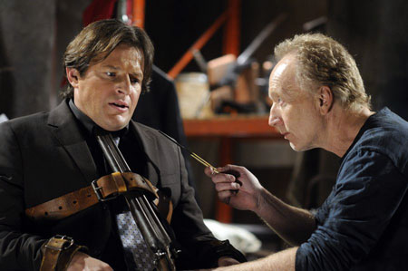 A movie screenshot of Jigsaw talking to Detective Hoffman as he is tied to a chair with a shotgun pointed at himself