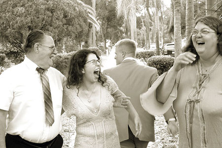 An old sepia picture of a man and two women in hysterics with laughter