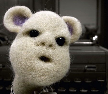 A photograph of a white furry-faced toy with a gormless look on his face